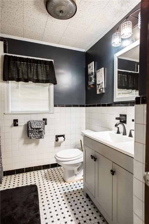 1405 Grove Ave, Waycross, GA 31501 - bathroom featuring tile walls, vanity, toilet, tile patterned flooring, and a wainscoted wall