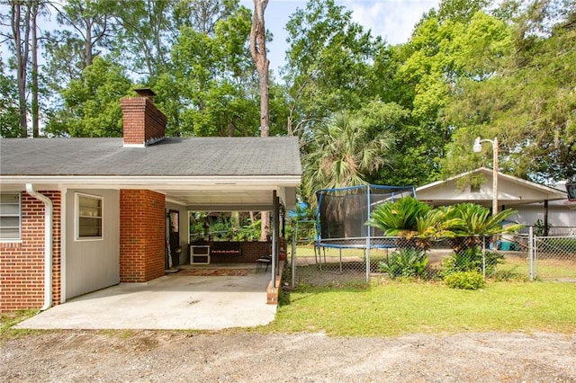 1405 Grove Ave, Waycross, GA 31501 - exterior space with a chimney, a carport, brick siding, a trampoline, and driveway