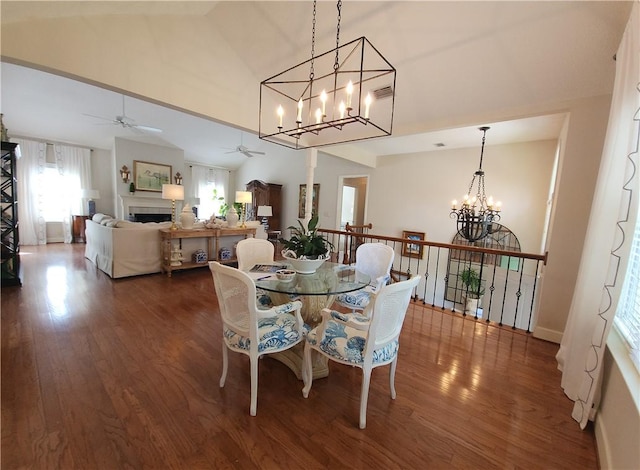 412 Palm Dr, Saint Simons Island, GA 31522 - dining space featuring a chandelier, a ceiling fan, dark wood-style flooring, a fireplace, and high vaulted ceiling