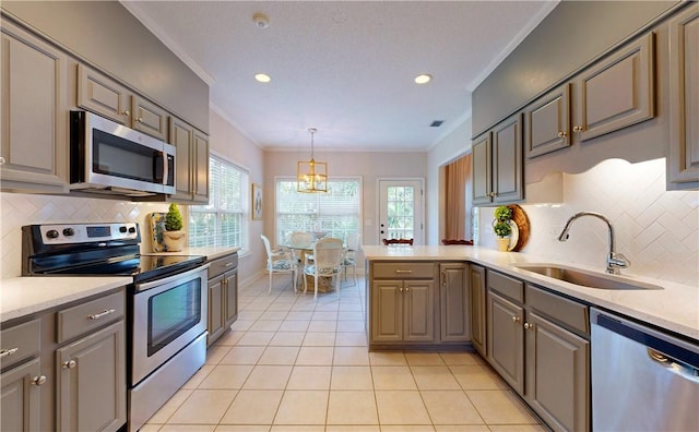 412 Palm Dr, Saint Simons Island, GA 31522 - kitchen with appliances with stainless steel finishes, crown molding, gray cabinetry, a peninsula, and light tile patterned floors