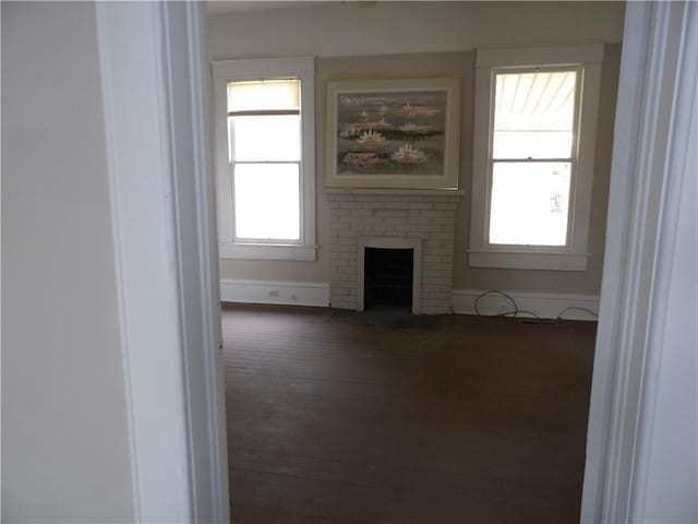 unfurnished living room with dark hardwood / wood-style flooring and a brick fireplace