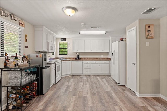 127 Landover Dr, Brunswick, GA 31525 - kitchen featuring white appliances, light wood-type flooring, white cabinetry, a textured ceiling, and a sink
