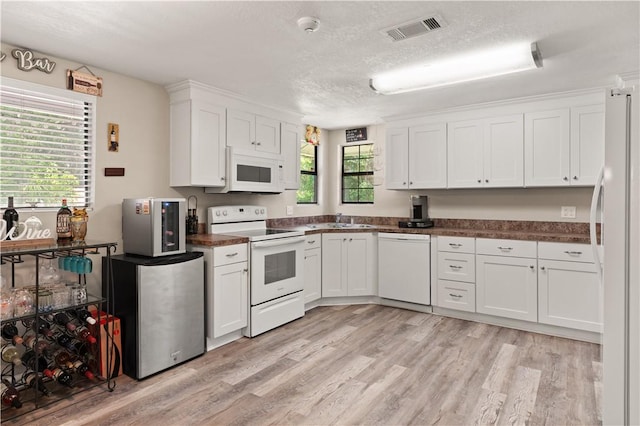 127 Landover Dr, Brunswick, GA 31525 - kitchen with white appliances, white cabinetry, light wood-style flooring, plenty of natural light, and a textured ceiling