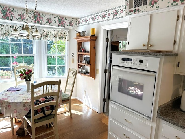 kitchen featuring pendant lighting, oven, white cabinetry, and hardwood / wood-style floors