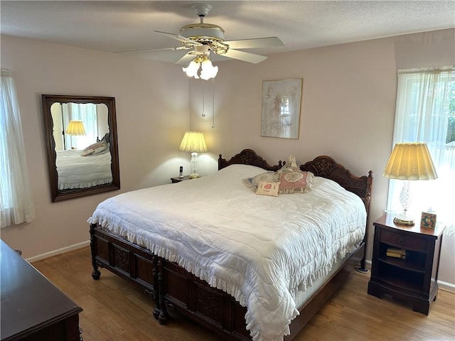 bedroom featuring ceiling fan, wood-type flooring, and multiple windows