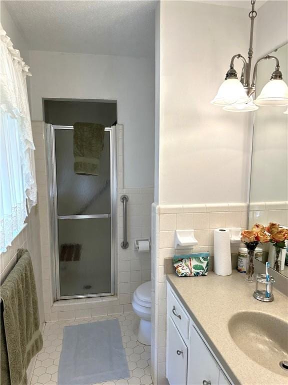 bathroom featuring tile patterned floors, walk in shower, vanity, tile walls, and toilet