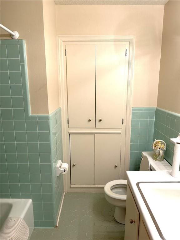 bathroom with tile patterned flooring, vanity, toilet, and tile walls