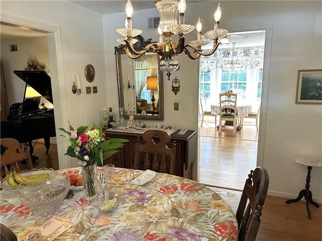 dining room featuring wood-type flooring, a textured ceiling, and an inviting chandelier