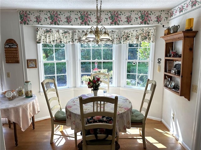 dining area featuring wood-type flooring, a textured ceiling, and an inviting chandelier