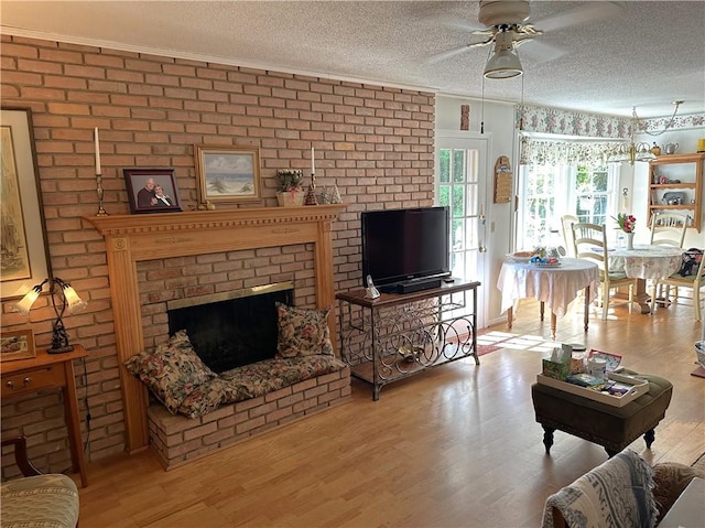 living room with light wood-type flooring, a textured ceiling, and a brick fireplace