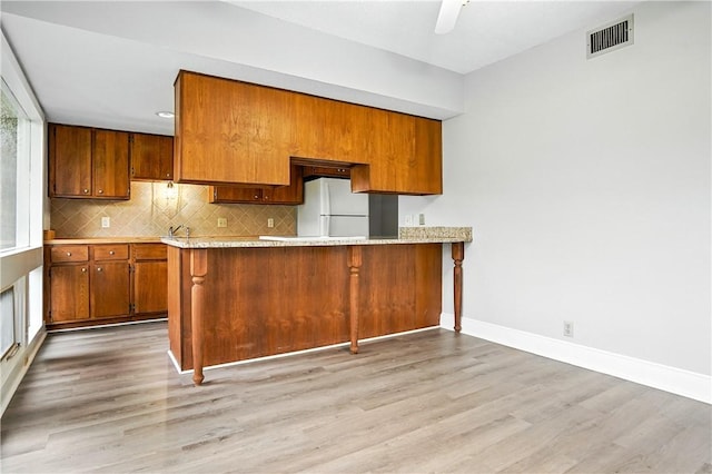 422 Fairway Villas Dr, Saint Simons Island, GA 31522 - kitchen featuring brown cabinetry, freestanding refrigerator, light wood-style floors, and light countertops