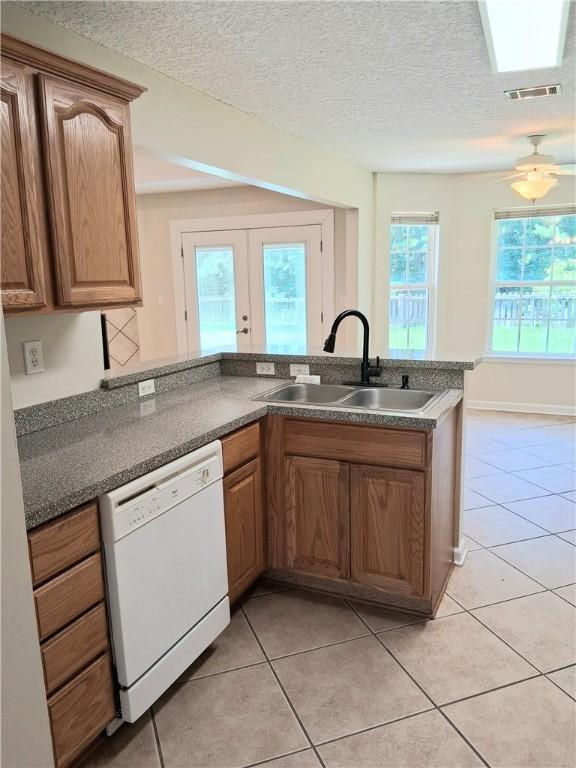 43 Shadowlake Ct, Brunswick, GA 31525 - kitchen with dishwasher, light tile patterned floors, dark countertops, brown cabinetry, and a textured ceiling