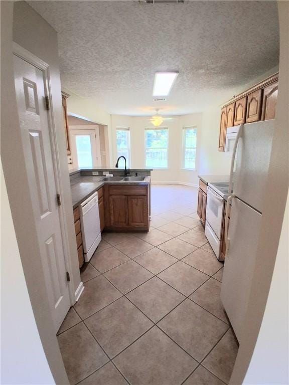 43 Shadowlake Ct, Brunswick, GA 31525 - kitchen featuring white appliances, a peninsula, light tile patterned flooring, a textured ceiling, and brown cabinets