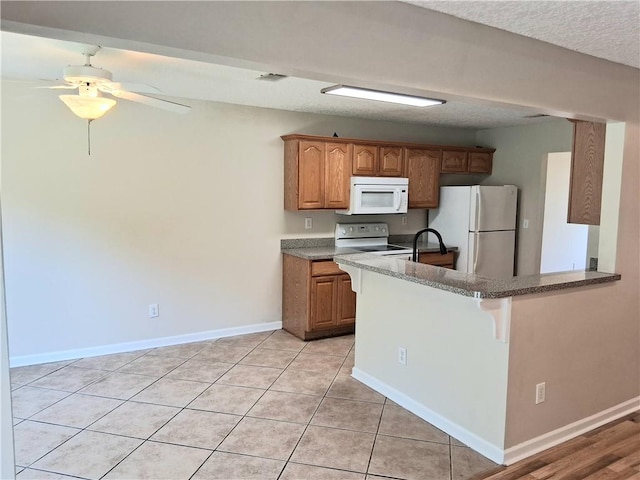 43 Shadowlake Ct, Brunswick, GA 31525 - kitchen featuring white appliances, a kitchen breakfast bar, ceiling fan, a peninsula, and brown cabinetry