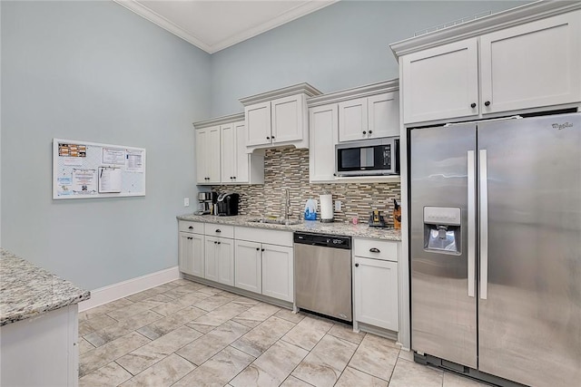 kitchen with backsplash, crown molding, light stone countertops, a sink, and stainless steel appliances