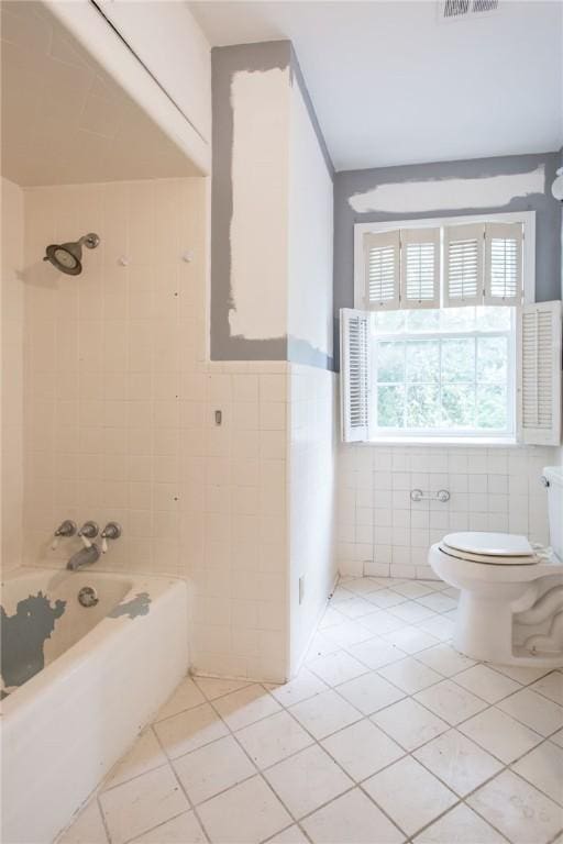 1701 Satilla Blvd, Waycross, GA 31501 - bathroom with tile walls, tile patterned flooring, toilet, washtub / shower combination, and a wainscoted wall