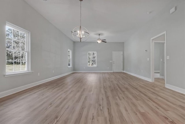 empty room with ceiling fan with notable chandelier and light hardwood / wood-style floors