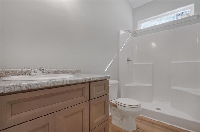 bathroom featuring a shower, toilet, vanity, and hardwood / wood-style flooring