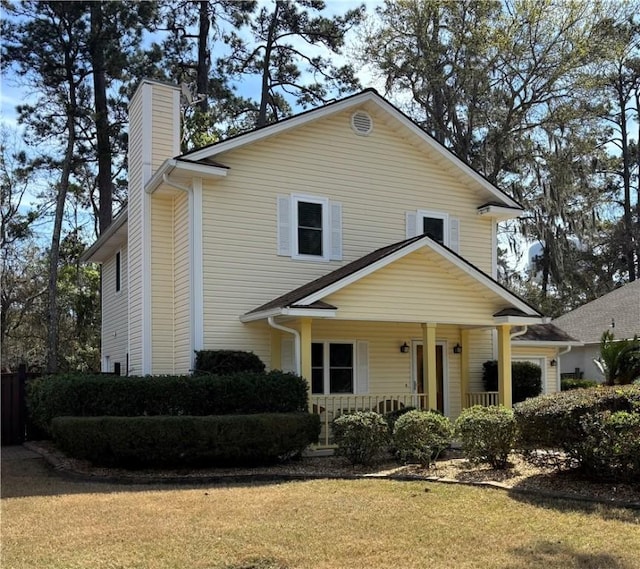 view of front of property with a porch, a front yard, and a chimney