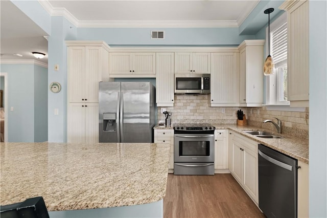 kitchen with light stone countertops, appliances with stainless steel finishes, hanging light fixtures, and sink