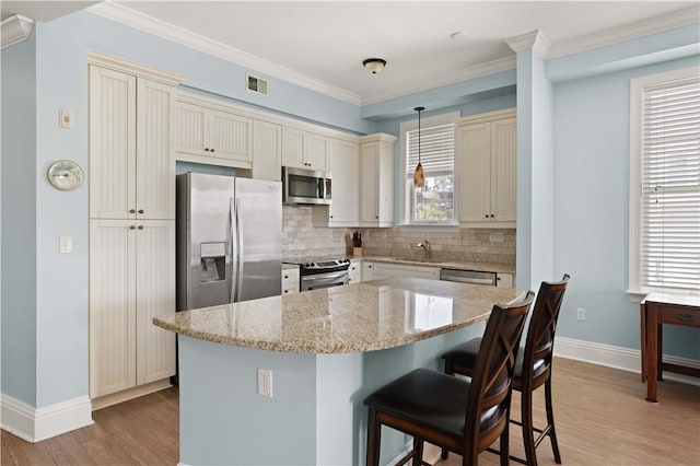 kitchen featuring a wealth of natural light, stainless steel appliances, decorative light fixtures, light hardwood / wood-style flooring, and a center island