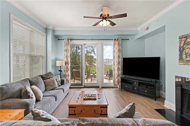 living room featuring light wood-type flooring, ceiling fan, and ornamental molding