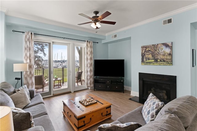 living room featuring ceiling fan, crown molding, and light hardwood / wood-style flooring