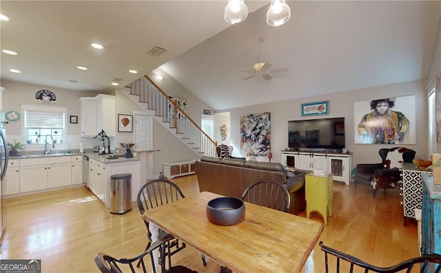 dining area featuring ceiling fan, light hardwood / wood-style floors, sink, and vaulted ceiling