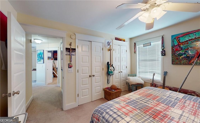 bedroom with multiple windows, ceiling fan, light colored carpet, and multiple closets