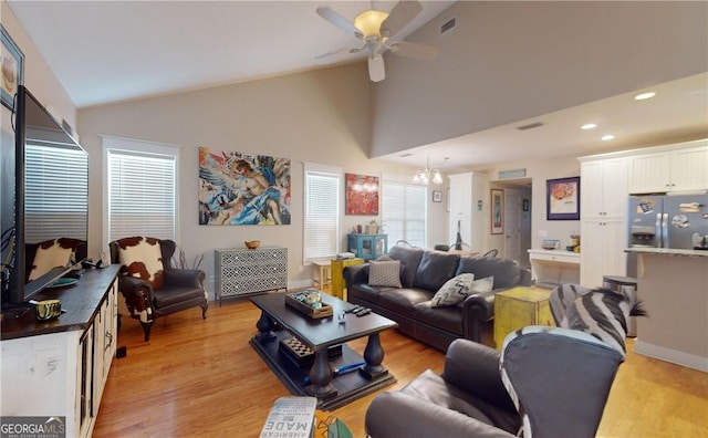 living room featuring ceiling fan with notable chandelier, a healthy amount of sunlight, and light wood-type flooring