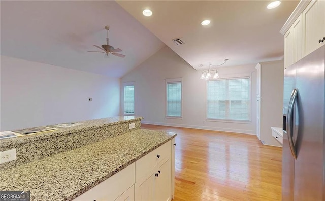 kitchen with white cabinetry, light stone countertops, stainless steel fridge, light hardwood / wood-style floors, and ceiling fan with notable chandelier