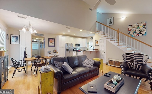 living room with light hardwood / wood-style floors, vaulted ceiling, and an inviting chandelier