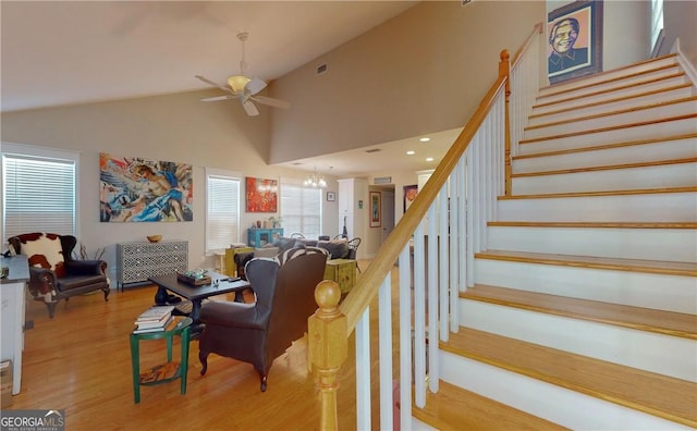 living room featuring ceiling fan with notable chandelier, high vaulted ceiling, and light hardwood / wood-style flooring