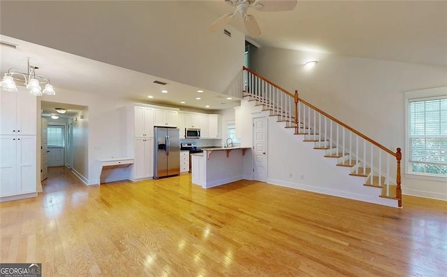 kitchen with white cabinets, sink, light wood-type flooring, appliances with stainless steel finishes, and kitchen peninsula