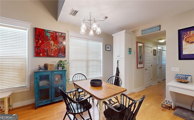 dining area featuring light wood-type flooring and an inviting chandelier