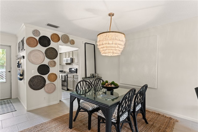 tiled dining room featuring a notable chandelier and ornamental molding