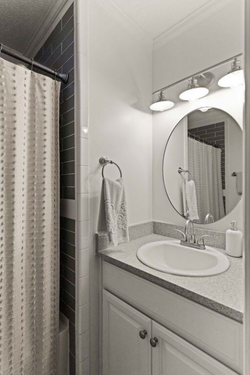 bathroom with a textured ceiling, vanity, and crown molding