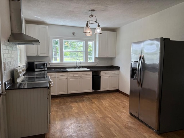 4427 Pine Valley Rd, Waycross, GA 31503 - kitchen featuring appliances with stainless steel finishes, wall chimney range hood, wood finished floors, white cabinetry, and a textured ceiling