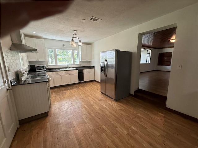 4427 Pine Valley Rd, Waycross, GA 31503 - kitchen featuring stainless steel appliances, wall chimney exhaust hood, dark countertops, wood finished floors, and white cabinets