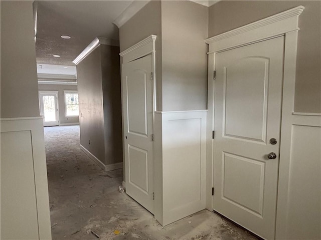 hall featuring ornamental molding, wainscoting, and a decorative wall