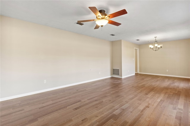 spare room with hardwood / wood-style floors and ceiling fan with notable chandelier