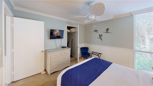 bedroom with ceiling fan, a closet, a textured ceiling, and ornamental molding