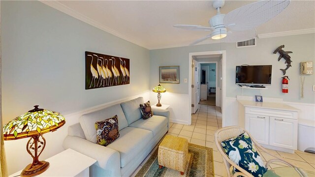 tiled living room with ceiling fan and ornamental molding