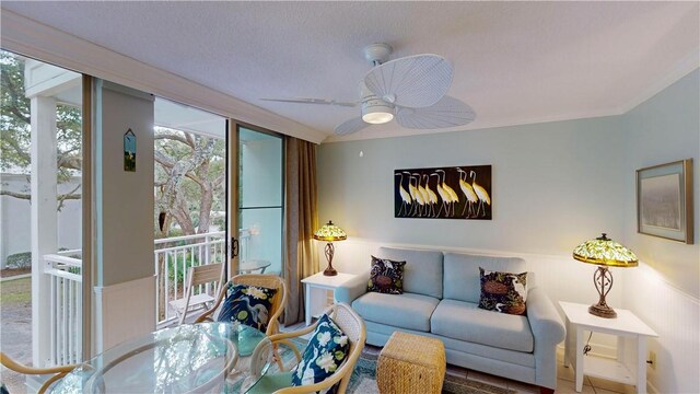 living room with a textured ceiling, ceiling fan, and crown molding