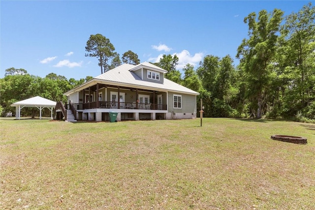 back of house featuring a gazebo, a deck, a lawn, a detached carport, and metal roof