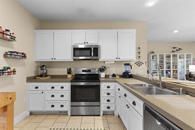 kitchen featuring white cabinetry, a sink, light countertops, stainless steel appliances, and light tile patterned flooring