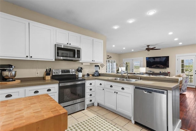 kitchen featuring a ceiling fan, a peninsula, butcher block countertops, a sink, and stainless steel appliances