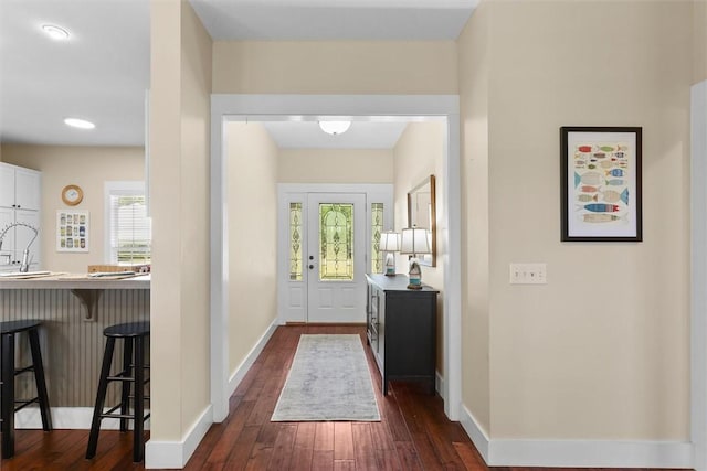 doorway with baseboards, dark wood finished floors, and a sink