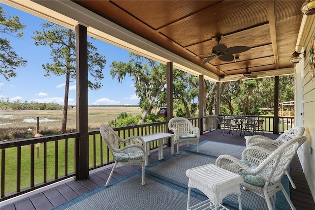 wooden terrace with a lawn, a rural view, and a ceiling fan