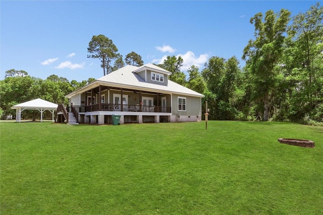 rear view of property featuring a lawn, a gazebo, a ceiling fan, and a wooden deck
